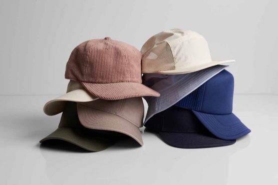 Pile of AS Colour hats, ideal for custom printing and embroidery, showcasing style and versatility.